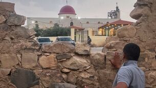 A man looks through a gap in a stone wall toward a Greek Orthodox church where gunmen opened fire during a funeral hours earlier in Hamoud village, in Jordan’s Karak governorate (AP) A man looks through a gap in a stone wall toward a Greek Orthodox church where gunmen opened fire during a funeral hours earlier in Hamoud village, in Jordan’s Karak governorate (AP)