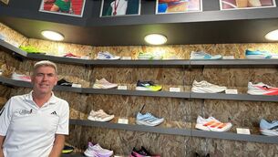 <p>Conor Kavanagh underneath a wall of fame at John Buckley Sports.</p>