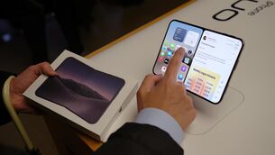 <p>A person interacting with an iPhone Duo at an Apple store. Apple says the foldable iPhone has had an 'incredibly positive' response from consumers. Picture: Yui Mok/Press Association</p>