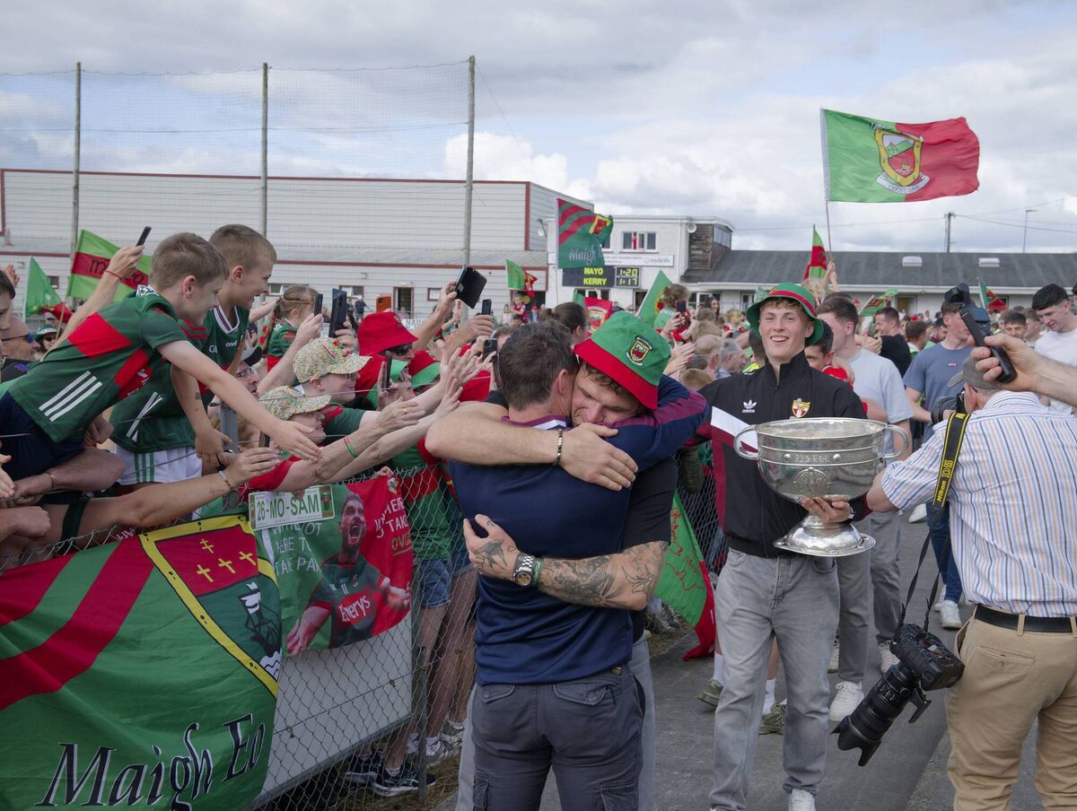 Mayo star Jordan Flynn embraces his Crossmolina manager Brian Benson at the homecoming at St Tiernan’s Park, home of Crossmolina Deel Rovers. Kobe McDonald, holding Sam Maguire, is just behind him. Pic: Michael McLaughlin Mayo star Jordan Flynn embraces his Crossmolina manager Brian Benson at the homecoming at St Tiernan’s Park, home of Crossmolina Deel Rovers. Kobe McDonald, holding Sam Maguire, is just behind him. Pic: Michael McLaughlin