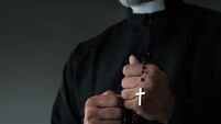 Close up of a priest holding rosary and praying
