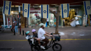 Israeli flags hang at a shop as a bicyclist carrying children passes by (AP Photo/David Goldman) Israeli flags hang at a shop as a bicyclist carrying children passes by (AP Photo/David Goldman)