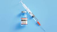 Shingles Vaccine and Syringe On Blue Background