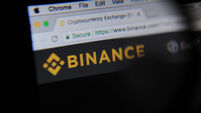 The cryptocurrency exchange website Binance is seen through a magnifying glass