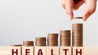 Hand putting coins on stack stair as step growing growth and wooden cube block with word HEALTH. Investment health and insurance