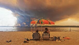 <p>Beachgoers sit on the beach of Moutchic in Lacanau, southwestern France on July 24, 2026, as clouds of smoke rise into the sky from a wildfire. Scientists have long warned that climate change caused by human use of fossil fuels will make periods of drought more intense and longer-lasting, creating the ideal conditions for wildfires. Picture: Maximilien LAMY / AFP via Getty Images</p> <p>Beachgoers sit on the beach of Moutchic in Lacanau, southwestern France on July 24, 2026, as clouds of smoke rise into the sky from a wildfire. Scientists have long warned that climate change caused by human use of fossil fuels will make periods of drought more intense and longer-lasting, creating the ideal conditions for wildfires. Picture: Maximilien LAMY / AFP via Getty Images</p>