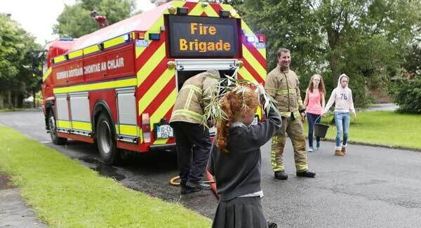 Six-year-old Sarah Horkan, Fairyfield, Parteen, Co Clare shelters from the rain as the fire brigade distribute water to households in the area. Pic: Press 22