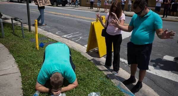 From left, Jeremy Dubach, Gigi Greaves and Joe Greaves pray for victims a few blocks from a crime scene at the nightclub where the mass shooting took place the night before in Orlando. Pic: AP