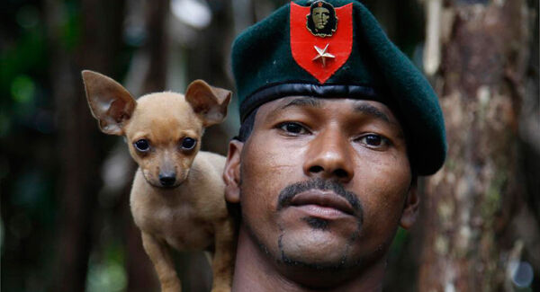 A rebel soldier of the 48th Front of the Revolutionary Armed Forces of Colombia, or FARC, poses for a photo with his dog in the southern jungles of Putumayo, Colombia.