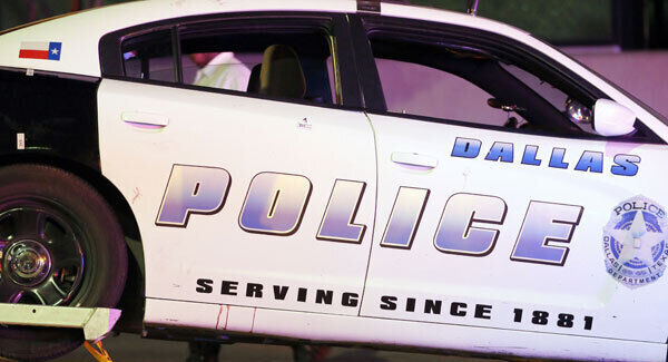 A Dallas police vehicle that has damage to the upper rear door and a red fluid stain beneath the same door is hauled away. Picture: AP Photo/Tony Gutierrez