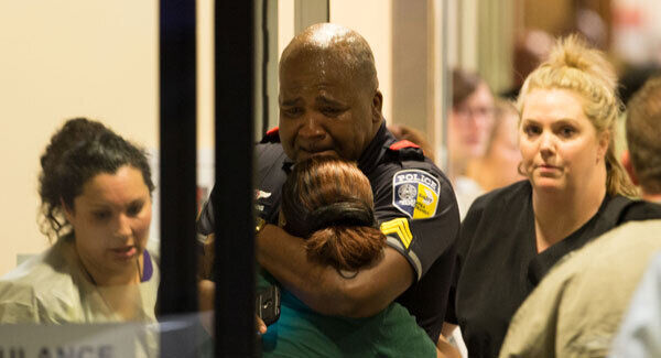 A Dallas Area Rapid Transit police officer receives comfort at the Baylor University Hospital emergency room entrance. Picture: Ting Shen/The Dallas Morning News via AP.