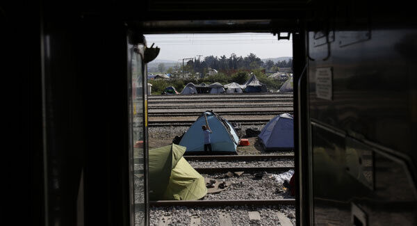 A migrant boy fixes his tent at the border crossing at the northern Greek border point of Idomeni, Greece, today. Pic: AP