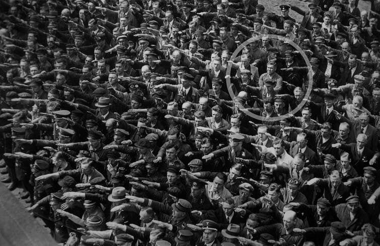 People giving a Nazi salute, with an unidentified person (possibly August Landmesser or Gustav Wegert) refusing to do so. wikipedia, CC BY-SA