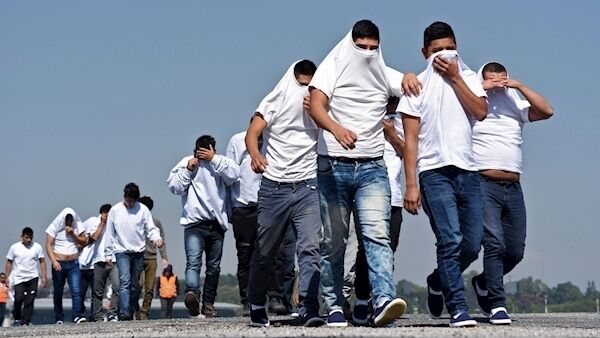 Guatemalan migrants deported from the United States cover their faces as they walk upon their arrival at the Air Force Base in Guatemala City on November 21, 2019. (Photo by ORLANDO ESTRADA/AFP via Getty Images)