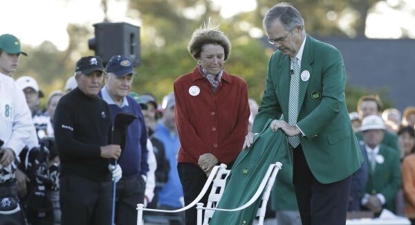Billy Payne, chairman of Augusta National Golf Club, with Kathleen "Kit" Gawthrop, wife of Arnlold Palmer, place a green jacket on a chair to honor Arnold Palmer before the first round for the Masters golf tournament
