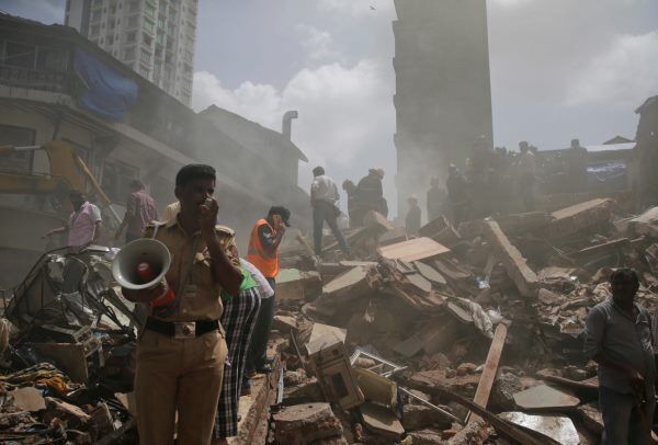 A policeman makes an announcement on a loudspeaker at the site of building collapse. A policeman makes an announcement on a loudspeaker at the site of building collapse.