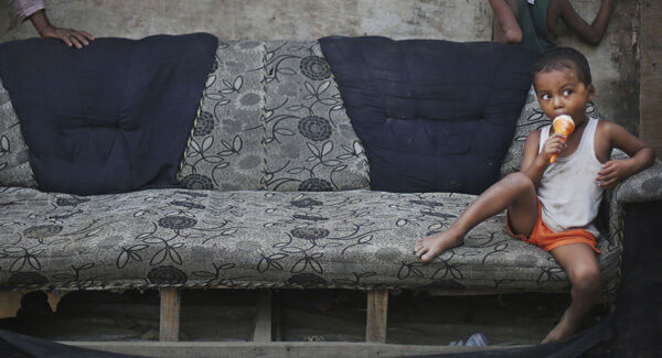A young Rohingya refugee boy eats an ice cream as he sits on a damaged sofa at a camp for refugees in New Delhi, India. A young Rohingya refugee boy eats an ice cream as he sits on a damaged sofa at a camp for refugees in New Delhi, India.