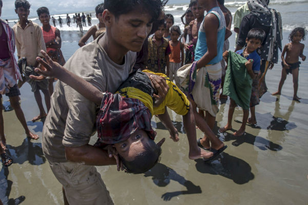 A man shakes a Rohingya Muslim boy while trying to revive him after the boat he was traveling in capsized just before reaching shore at Shah Porir Dwip, Bangladesh. The boy survived. AP Photo/Dar Yasin A man shakes a Rohingya Muslim boy while trying to revive him after the boat he was traveling in capsized just before reaching shore at Shah Porir Dwip, Bangladesh. The boy survived. AP Photo/Dar Yasin