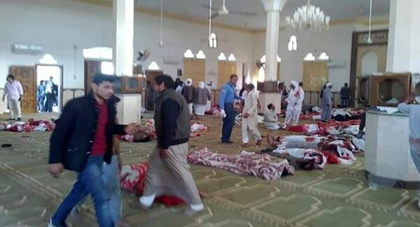 Egyptians walk past bodies following a gun and bombing attack at the Rawda mosque. (STRINGER/AFP/Getty Images)