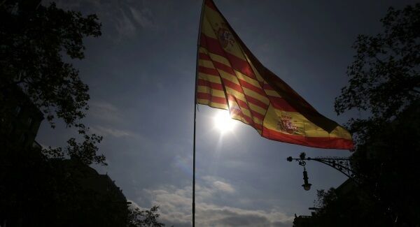 A person holds a pole with the flags of Catalonia and Spain as people celebrate "Dia de la Hispanidad", or Spain's National Day, in Barcelona. A person holds a pole with the flags of Catalonia and Spain as people celebrate "Dia de la Hispanidad", or Spain's National Day, in Barcelona.