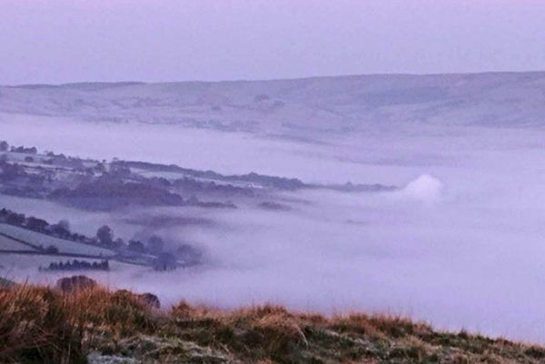 A plume of smoke rising through fog early this morning at the location of a house fire at a remote property in Wales. Photo: Jeremy Andrews/PA Wire