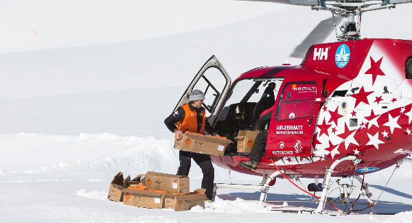 A worker from the slope patrol is reloading a helicopter of Air Zermatt with explosive material to throw it later out of the window during flight to artificially blow up avalanches at the skiing resort Belalp in Naters. Photo: Dominic Steinmann/Keystone via AP