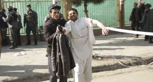 A wounded man is assisted at the site of an explosion in downtown Kabul, Afghanistan.