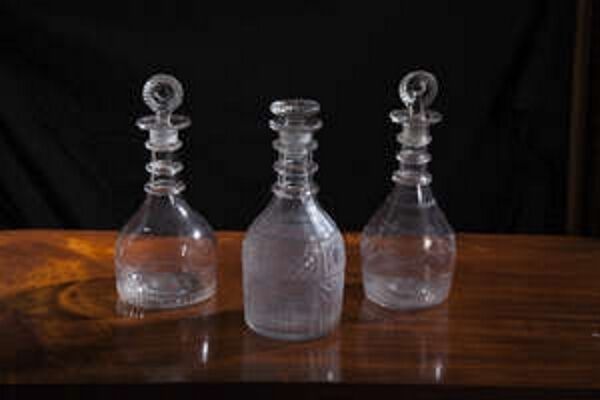 Two Cork Glass Company decanters with moulded target stoppers with another decanter.