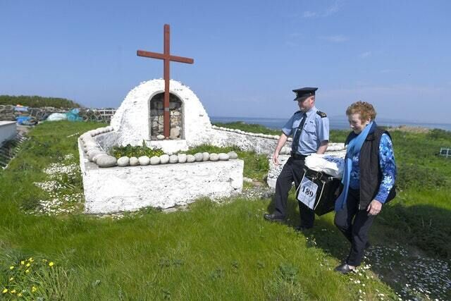 Garda Alan Gallagher and Presiding Officer Carmel McBride carry a polling box, used a day early by the few people that live off the coast of Donegal on the island of Inishbofin to vote in the referendum (Clodagh Kilcoyne/PA)