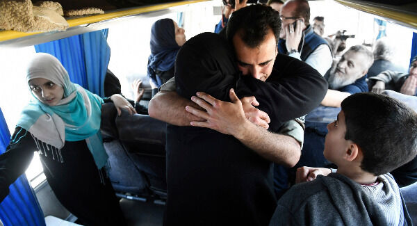 a Syrian government soldier hugs a woman inside a bus carrying released families who were held for years by al-Qaida-linked fighters. Pic: SANA via AP