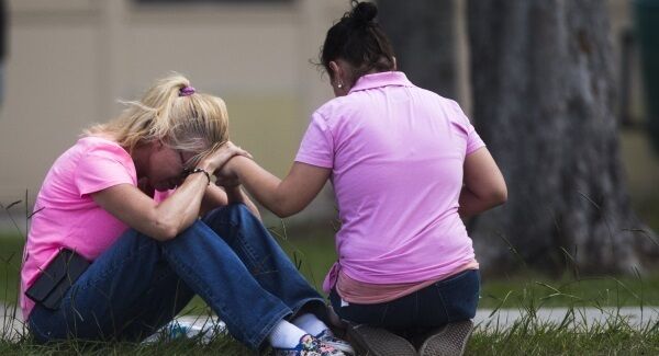 Two women pray outside the family reunification site following the shooting. Pic: AP Two women pray outside the family reunification site following the shooting. Pic: AP