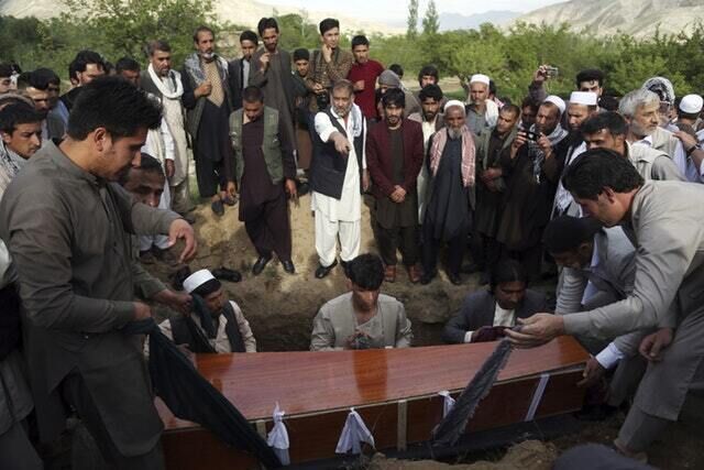 Relatives, colleagues and friends bury the body of AFP photographer Shah Marai (Rahmat Gul/AP)