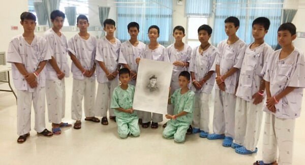 The rescued players pose with a sketch of the Thai navy diver who died while trying to rescue them (Ministry of Health/Chiang Rai Prachanukroh Hospital/AP)