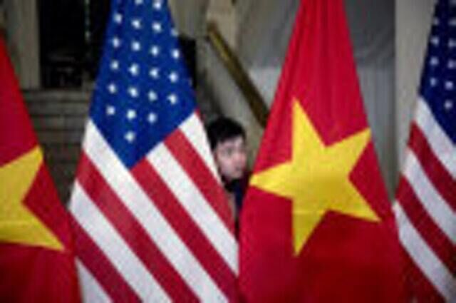 A worker helps arrange American and Vietnamese flags (Andrew Harnik/AP)