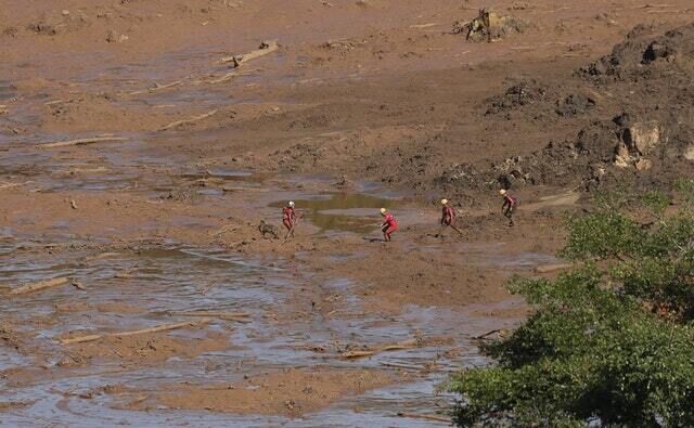 Rescue workers look for victims in the mud (Andre Penner/AP)