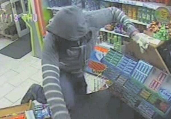Ian Horgan in Seán’s Shop in Limerick in 2013, with his hood up, a scarf covering his face, and wearing white gloves. Having spotted the manager stepping out of the shop briefly, Horgan seizes his chance and vaults the counter. His target was the cash register and the day’s takings.Picture: Courtesy of Mail on Sunday
