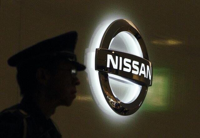 A security guard stands near the logo at Nissan Motor HQ (Eugene Hoshiko/AP)