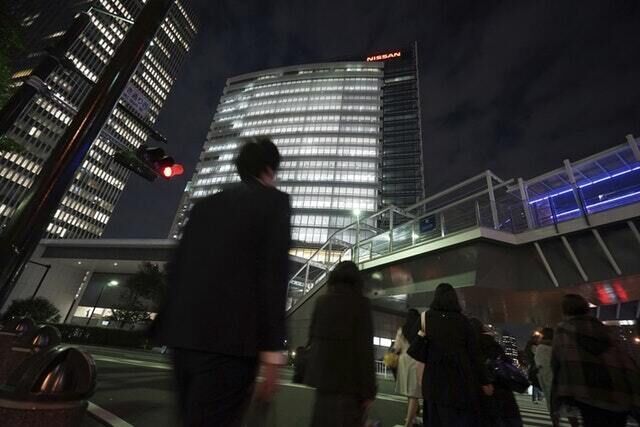 People walk by Nissan Motor  headquarters (Eugene Hoshiko/AP)