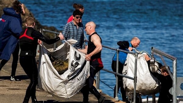 Volunteers haul rubbish from the Causeway Maid boat onto the dock at Ballintoy Harbour. Photo: Liam McBurney/PA