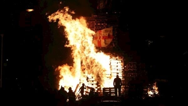 Crowds watch as a bonfire is lit in the New Lodge area of Belfast. Picture: PA Wire