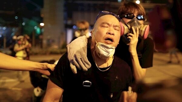 A protester is overcome by tear gas near the Shum Shui Po police station in Hong Kong today.
