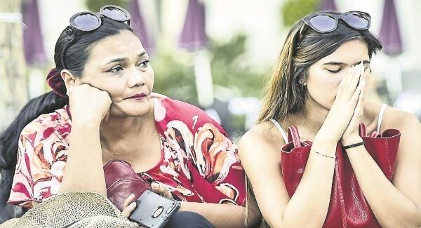 People reflect upon the horrific attack in Nice as they sit in front of tributes placed where bodies fell on the Promenade des Anglais. Pic: Ben Birchall/PA