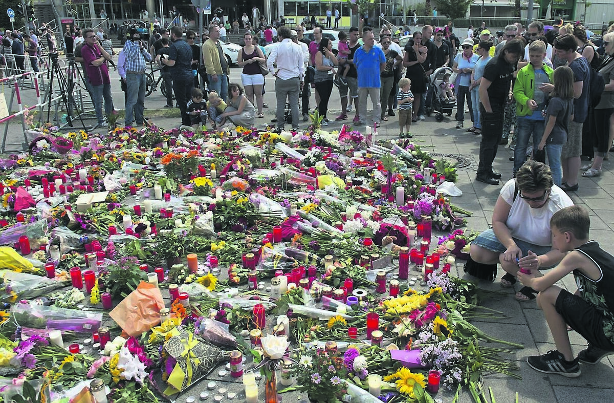 People pay their respects yesterday in front of the Olympia shopping centre in Munich, Germany, where a shooting left nine people dead. Pictures: Jens Meyer/AP