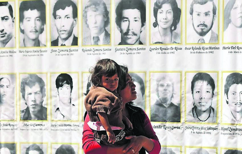 woman with her daughter observes the pictures of people who lost their lives during the Guatemalan civil war.