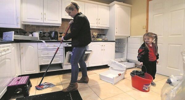 Aisling McAvoy gets a helping hand while cleaning the kitchen floor of her home in Glanmire. She says families in the estate could be waiting weeks for an insurance payout due to red tape.