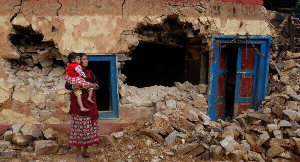 A woman and child outside a home destroyed by the 2015 earthquake