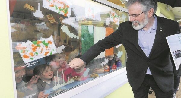 Sinn Féin president Gerry Adams waving to some of the staff and children looking out the window from the Little Learners Educare room as he left following a visit to Togher Family Centre, Cork. Picture: Denis Minihane