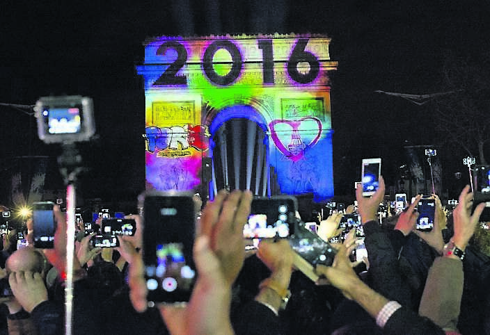 Revellers photograph the video performance projected on to the Arc de Triomphe as part of New Year’s Eve celebrations in Paris.
