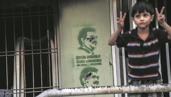 A boy shows V-signs near pictures of jailed Kurdish leader Abdullah Ocalan in the Kurdcontrolled Turkish city of Diyarbakir, where 15 neighbourhoods have been placed under curfew