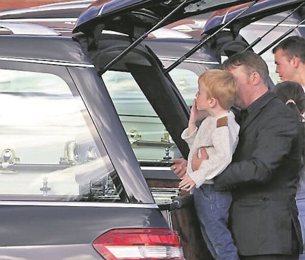 A young boy blows kisses to the caskets after the funeral Mass A young boy blows kisses to the caskets after the funeral Mass